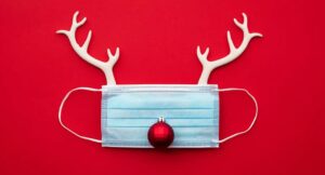 Mascarilla quirúrgica con cuernos de reno sobre fondo rojo, sobre cómo sobrellevar las navidades en pandemia